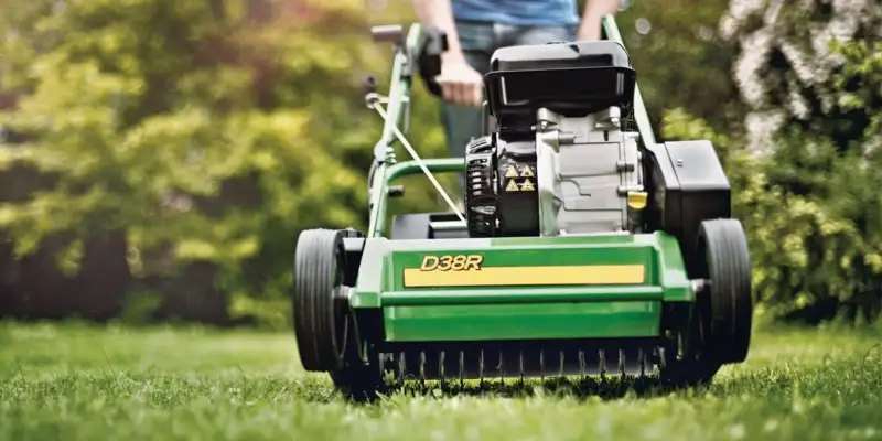 Een persoon die een verticuteermachine gebruikt op een gazon in de lente